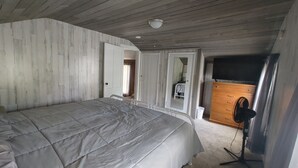 Un dormitorio con cama, armario de madera y ventilador de techo.