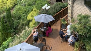 Une terrasse avec coin salon extérieur, entourée d’une végétation luxuriante et d’un vignoble.