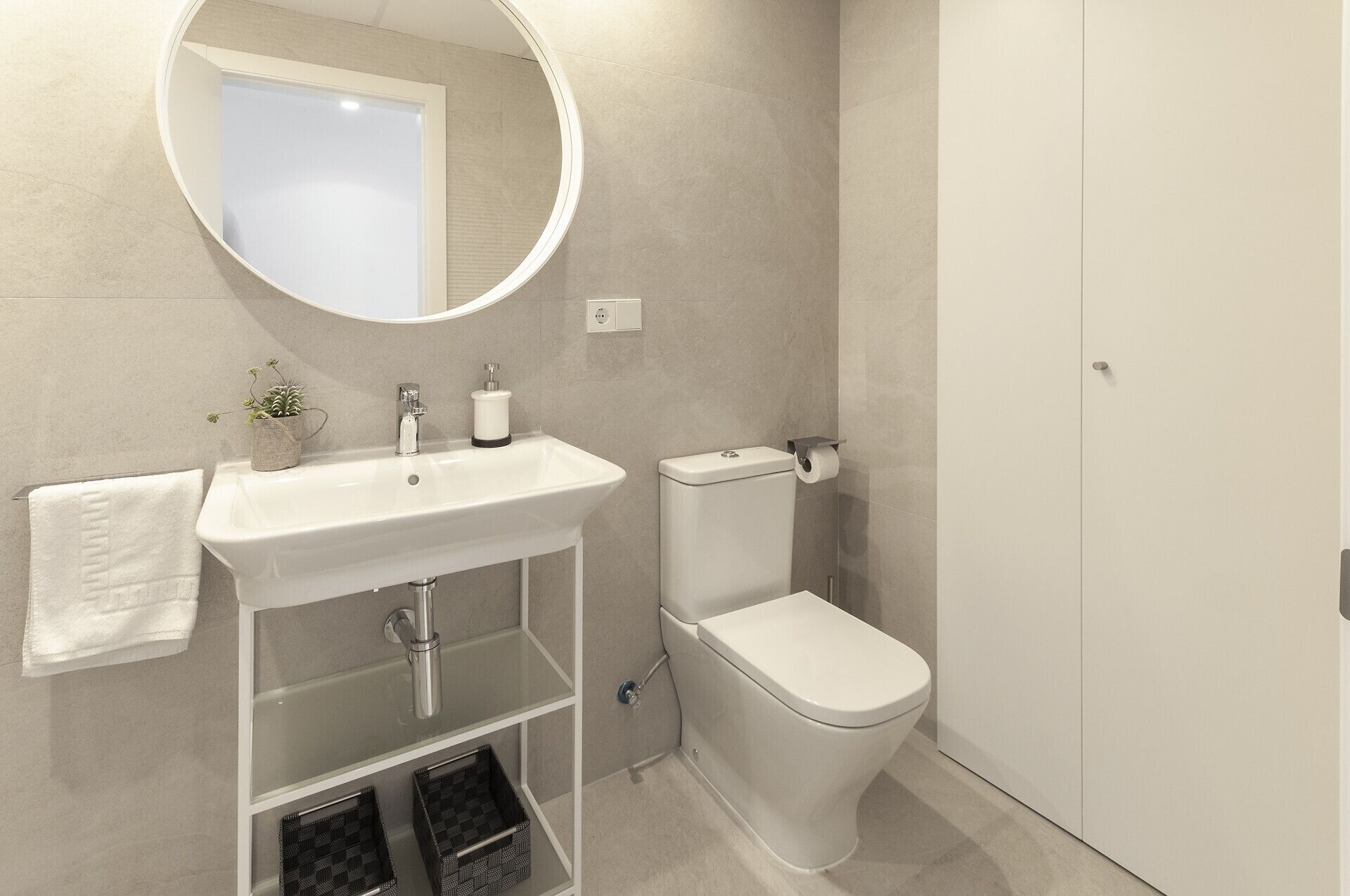Un bagno moderno con lavandino, specchio, servizi igienici e porta asciugamani bianchi.