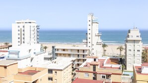 A coastal cityscape with high-rise buildings, a beach, and a clear sky.