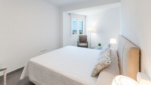 Une chambre d’hôtel avec un grand lit, une chaise, une table, une lampe et une fenêtre donnant sur la plage.