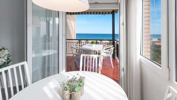 Un balcon avec une table et des chaises, une vue sur la mer et une balustrade.