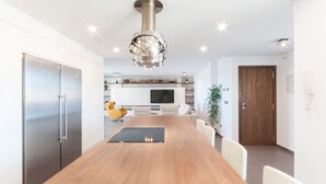 Una cocina moderna con una mesa de comedor de madera, armarios blancos y un horno empotrado.