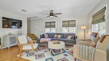 A modern living room with a sofa, chairs, a coffee table, and a ceiling fan.