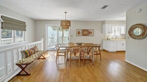 A spacious dining area with a wooden table and chairs, a bench with a striped cushion, and a wicker pendant light. - Large Deck/ in-law suite /Walk to Beach/ Location! (Panama City Beach)