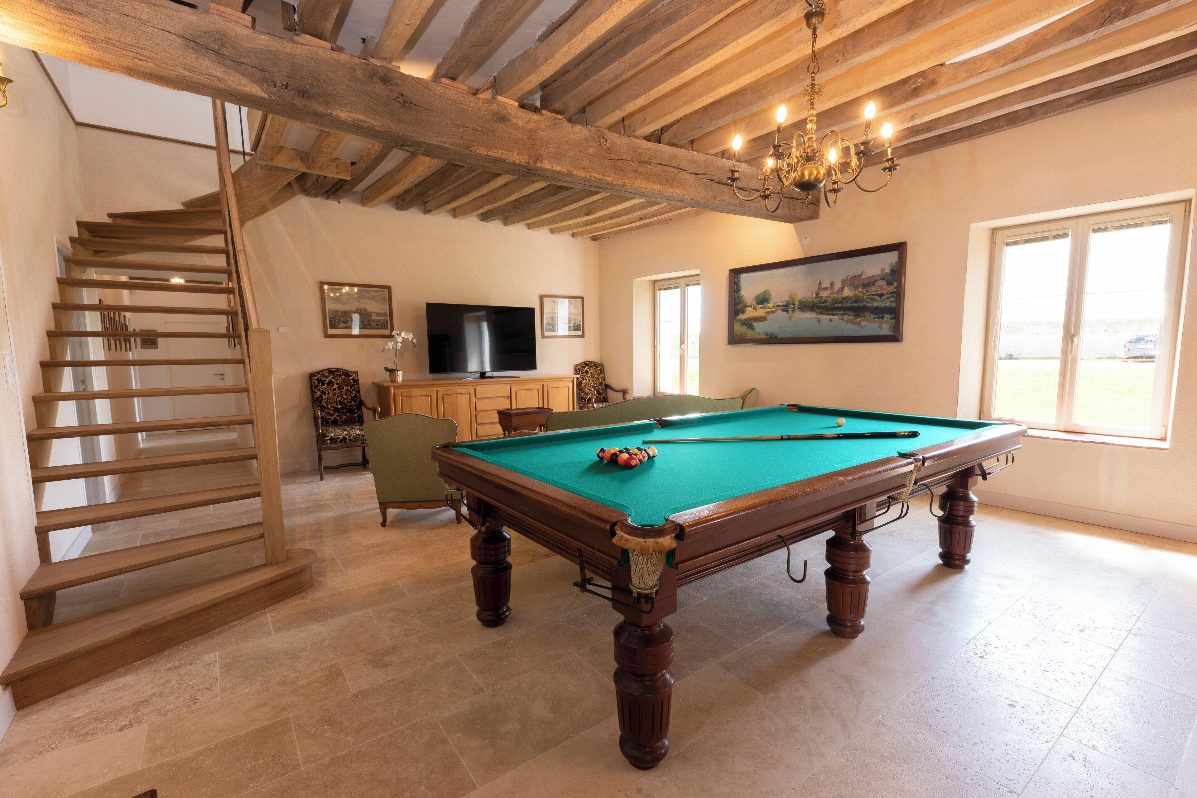A spacious room with a pool table, a television, and a painting on the wall.