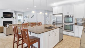 A modern kitchen with white cabinets, a central island with seating, stainless steel appliances, and pendant lighting. - 5 Bed on Cul-de-sac Downtown. Playground, Kayak Launch, Bike trails 1/2 block aw (Rehoboth Beach)