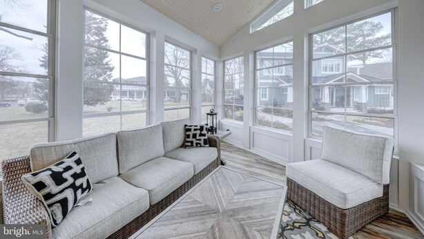 A sunroom with large windows, a sofa, a chair, and a patterned rug. - 5 Bed on Cul-de-sac Downtown. Playground, Kayak Launch, Bike trails 1/2 block aw (Rehoboth Beach)