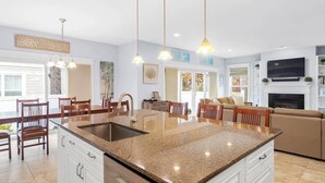 A modern kitchen with granite countertops, a central island, pendant lighting, and a dining area with wooden chairs. - 5 Bed on Cul-de-sac Downtown. Playground, Kayak Launch, Bike trails 1/2 block aw (Rehoboth Beach)