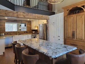 Eine moderne Küche mit Marmorarbeitsplatte, Holzschränken und einem Edelstahlkühlschrank.