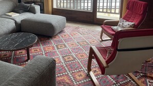 A living room with a sofa, armchair, and coffee table. A large window offers a view of a snowy outdoor area. - Spacious, comfortable apartment at the foot of the slopes (Arvieux)