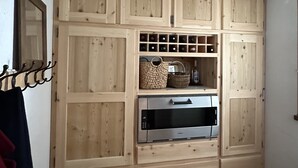 A kitchen with wooden cabinets, a built-in microwave, and a ceiling light fixture. - Spacious, comfortable apartment at the foot of the slopes (Arvieux)