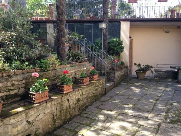 A stone staircase leading to a balcony with potted plants and a metal railing.