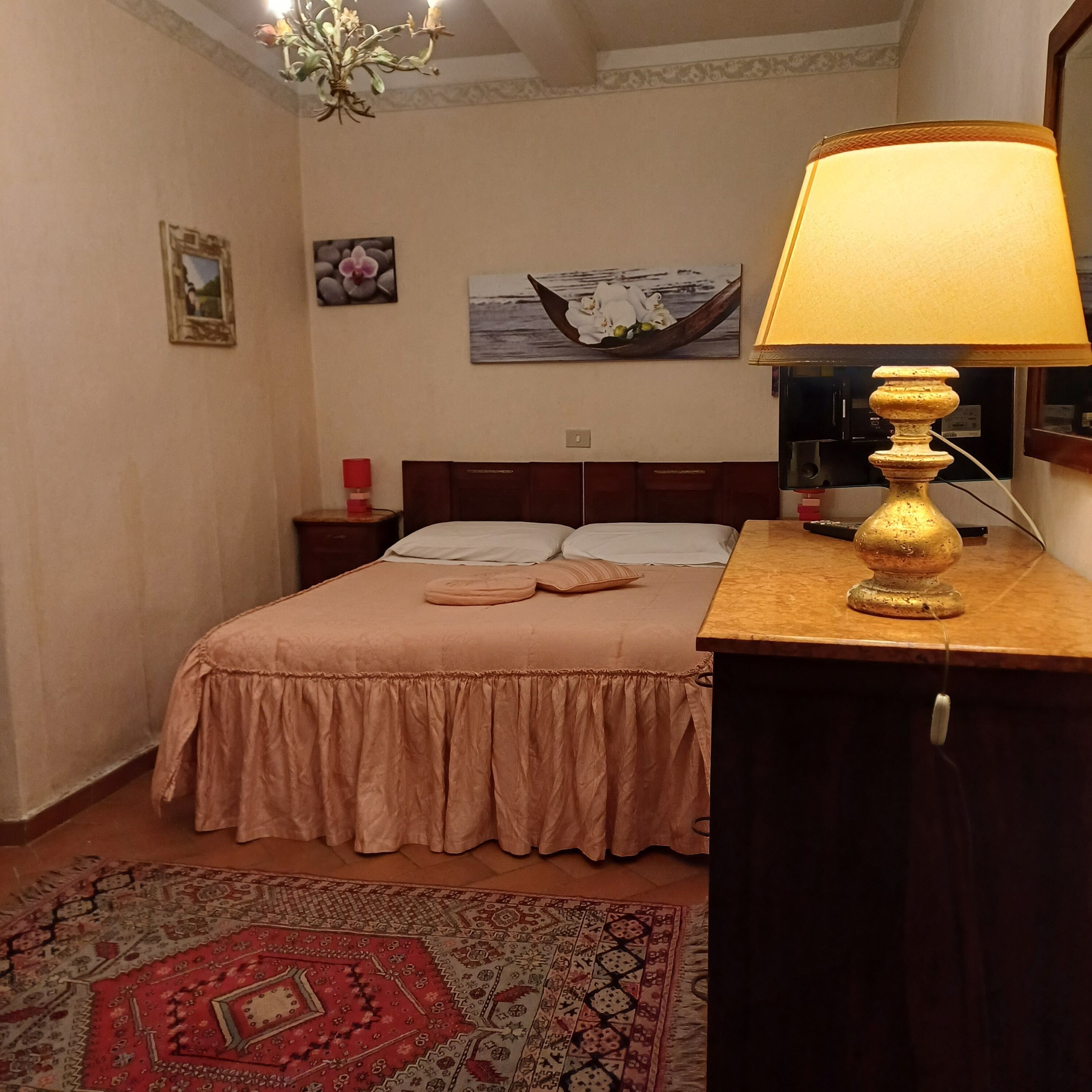 Ein ordentlich eingerichtetes Schlafzimmer mit einem Bett, einem Nachttisch mit Lampe, einem Teppich und einem Bild an der Wand.