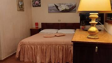 Ein ordentlich eingerichtetes Schlafzimmer mit einem Bett, einem Nachttisch mit Lampe, einem Teppich und einem Bild an der Wand.