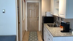 A compact kitchen with a microwave, sink, and coffee maker.