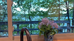 A kitchen with a modern faucet, a potted plant with lilac flowers, and a view of a wooden deck and trees through a window. - Steps from Beautiful Lake Michigamme (Michigamme Township)