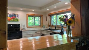 A modern kitchen with a wooden countertop, a built-in oven, a sink, and a window with a view of greenery. - Steps from Beautiful Lake Michigamme (Michigamme Township)