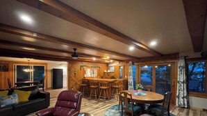 A spacious living area with a wooden ceiling, a dining table, leather chairs, and a bar area. - Steps from Beautiful Lake Michigamme (Michigamme Township)