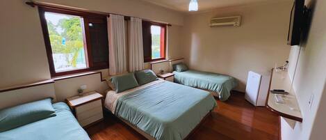 A room with two beds, a ceiling fan, an air conditioning unit, and a window with curtains.