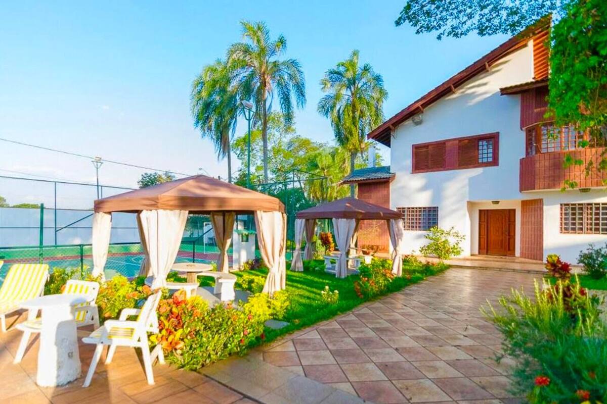 A patio area with outdoor seating and a gazebo, surrounded by lush greenery and palm trees.