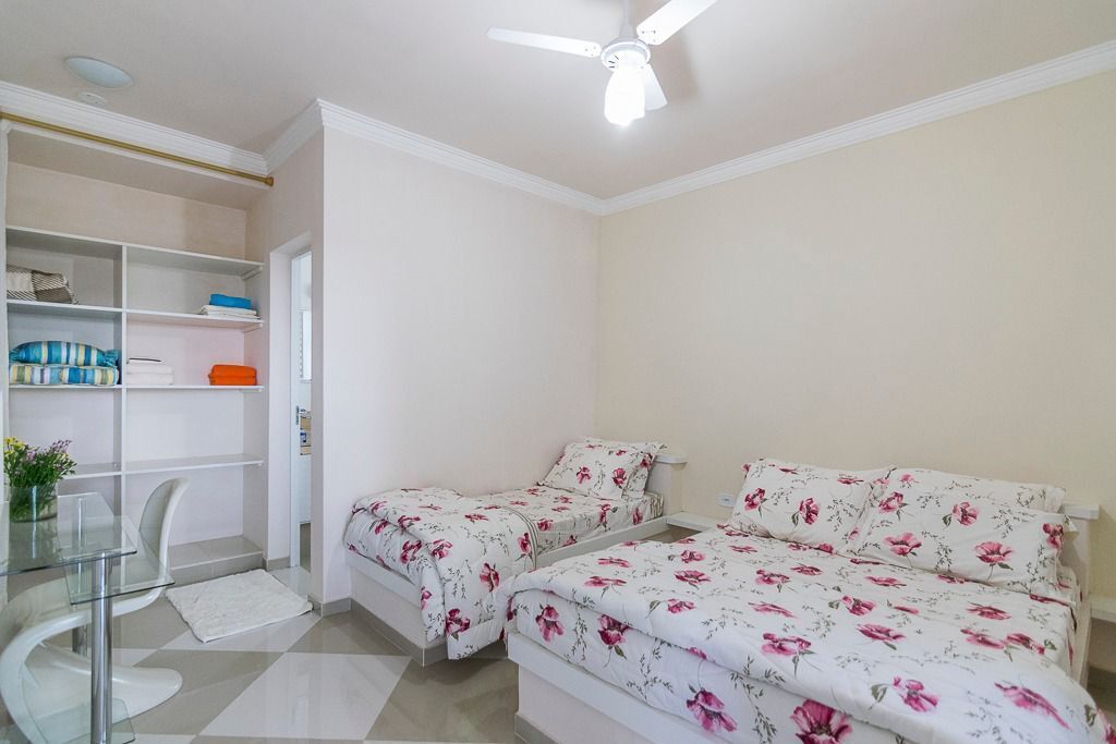 Een slaapkamer met twee bedden, een glazen bureau en een plafondventilator.