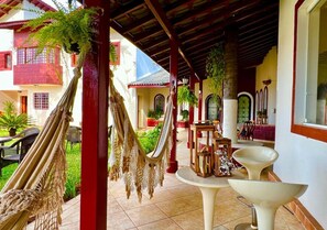 A covered outdoor area with hammocks, a white table, and a decorative shelf.