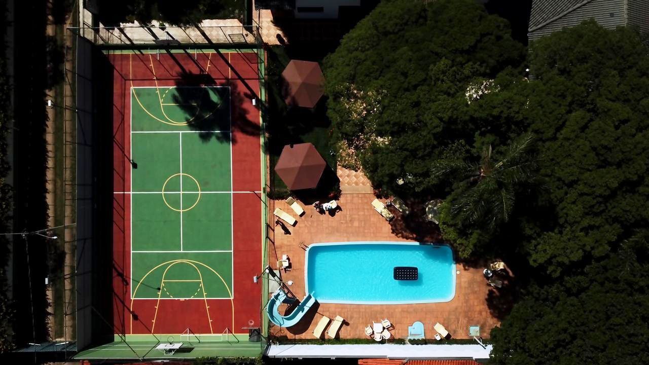 Vista aérea de una propiedad con cancha de baloncesto, piscina y mobiliario exterior.