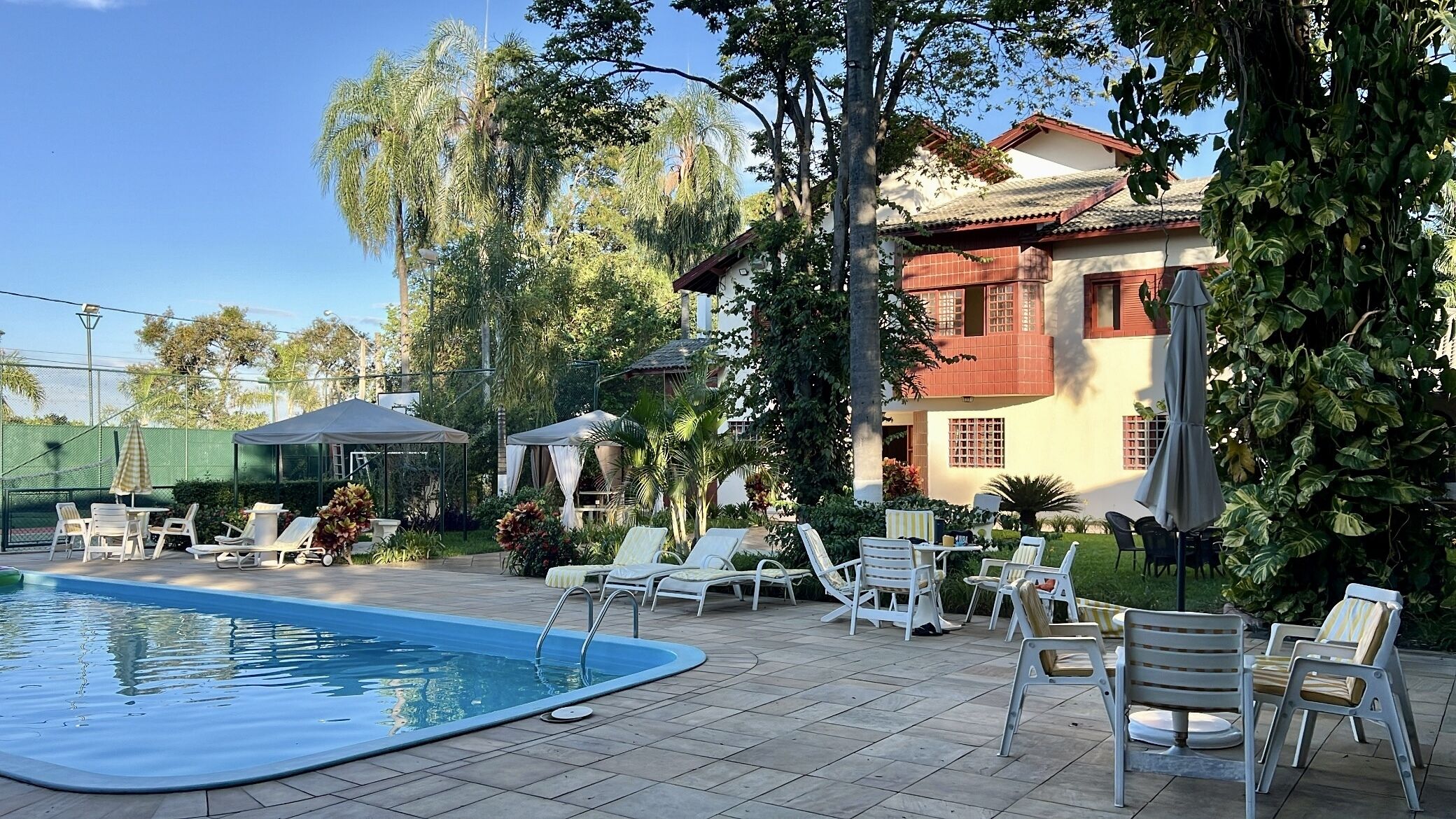A pool area with lounge chairs and a covered seating area.
