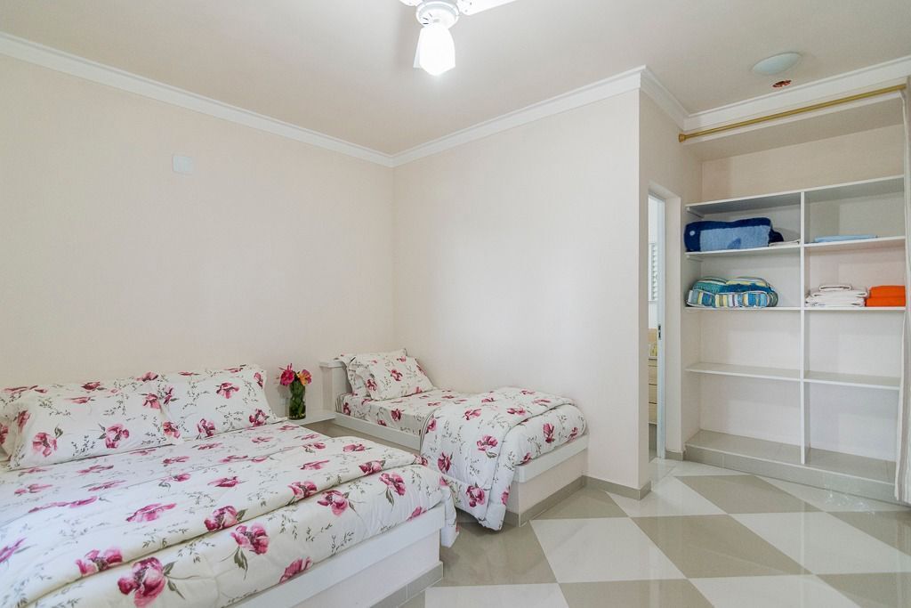A bedroom with two beds, a wardrobe, and a tiled floor.