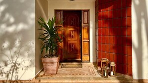 Una puerta de madera con un panel decorativo, una planta en maceta y una pared de azulejos.