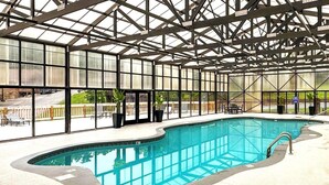 An indoor swimming pool with a glass ceiling, surrounded by a patio area with outdoor seating. -  Dollywood - Best Location & Value (Sevierville)