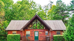 A log cabin with a green door, two windows, and a porch with railings. -  Dollywood - Best Location & Value (Sevierville)
