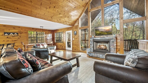 A spacious living room with leather sofas, a fireplace, and large windows offering a view of the outdoors. -  Dollywood - Best Location & Value (Sevierville)
