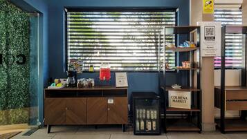 A coffee shop with a wooden counter, a coffee machine, and a refrigerator displaying beverages.