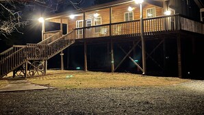 Una baita in legno con veranda e scale, dotata di illuminazione esterna.