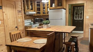 Una cucina in legno con isola centrale, pensili in legno, un forno a microonde e un frigorifero.