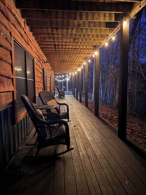 Een houten terras met rieten stoelen en een tafel, met uitzicht op een bebost gebied.