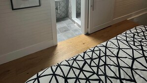 A bedroom with a bed, a wardrobe, a bathroom with a sink and mirror, and a framed picture on the wall.