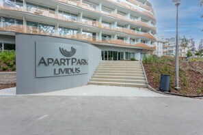 L’entrée d’un immeuble d’appartements moderne, avec une enseigne indiquant « APART PARK LIMUS ».