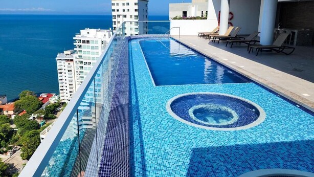 A rooftop infinity pool with a clear view of the ocean and surrounding buildings. - Polanco Residences Ambar Roca Santa Marta - Colombia (Santa Marta)