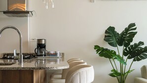 A modern kitchen with a central island, stainless steel appliances, and a coffee maker. - Polanco Residences Ambar Roca Santa Marta - Colombia (Santa Marta)