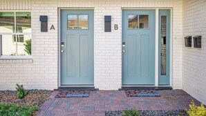 A two-story building with a white brick facade, two blue doors labeled 'A' and 'B', and a small window to the left.