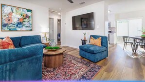 A modern living room with two blue sofas, a coffee table, and a large painting.