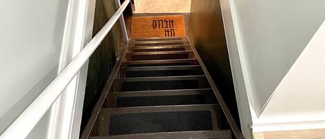 A staircase leading to a landing with a doormat.