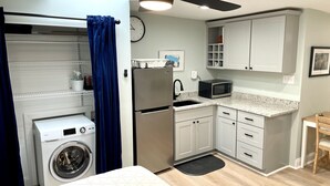 A compact kitchen with a washing machine, a microwave, and a sink. - Carriage House Studio in the Heart of DC (Washington)
