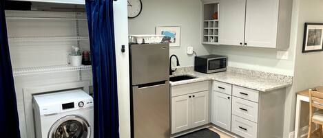 A compact kitchen with a washing machine, a microwave, and a refrigerator.