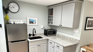 A compact kitchen with a refrigerator, microwave, sink, and cabinets. - Carriage House Studio in the Heart of DC (Washington)