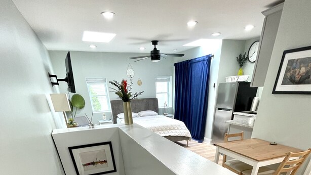 A modern apartment with a kitchen, dining area, and a bedroom with a large bed and a nightstand. - Carriage House Studio in the Heart of DC (Washington)