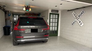 A garage with a car parked inside, a door labeled "WASHINGTON, D.C.", and a "CROSSING ROAD" sign on the wall. - Carriage House Studio in the Heart of DC (Washington)